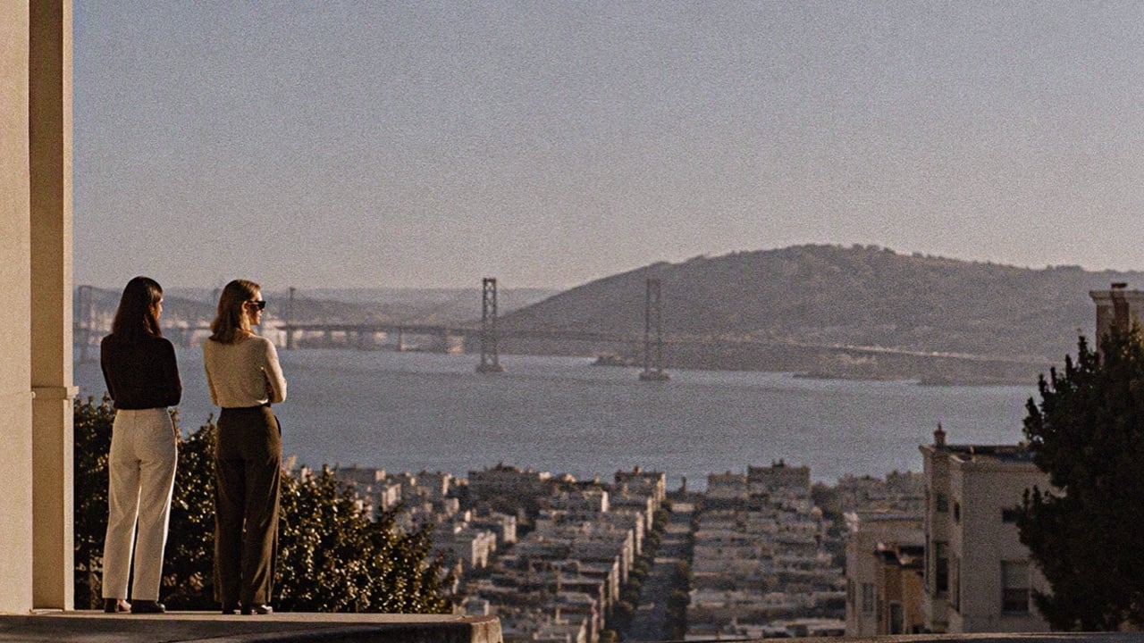 Two women standing side by side on a hill overlooking the San Francisco Bay and the Bay Bridge